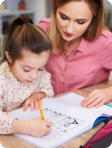 Adult helping a young child practise writing at a table