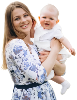 Smiling woman in a floral dress holding a baby in white outfit.